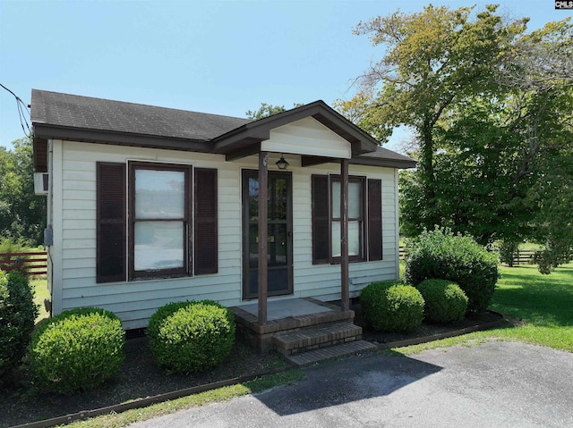 bungalow featuring fence and roof with shingles