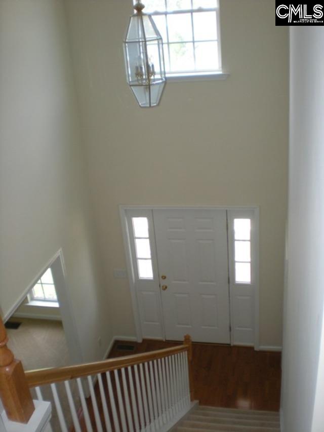 foyer with a wealth of natural light, wood-type flooring, and a notable chandelier