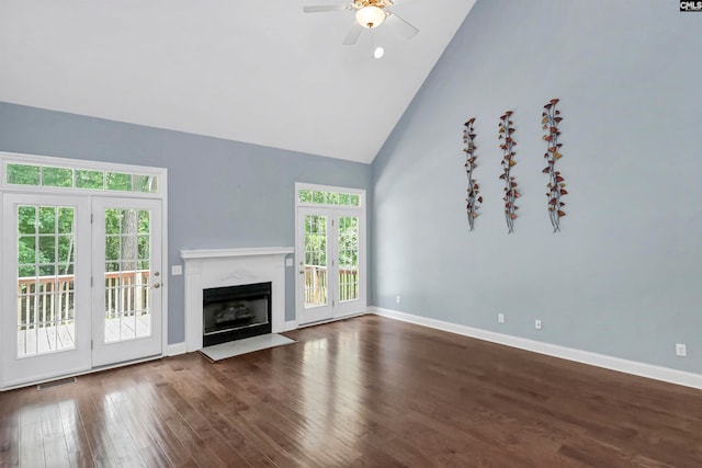 unfurnished living room featuring plenty of natural light, ceiling fan, a high end fireplace, and dark wood-type flooring