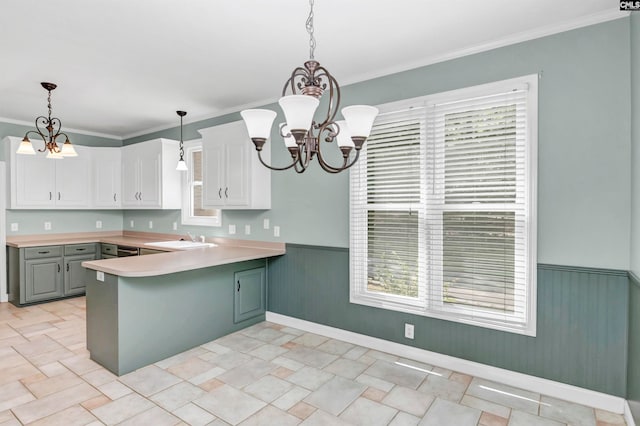 kitchen with white cabinets, pendant lighting, a notable chandelier, and ornamental molding