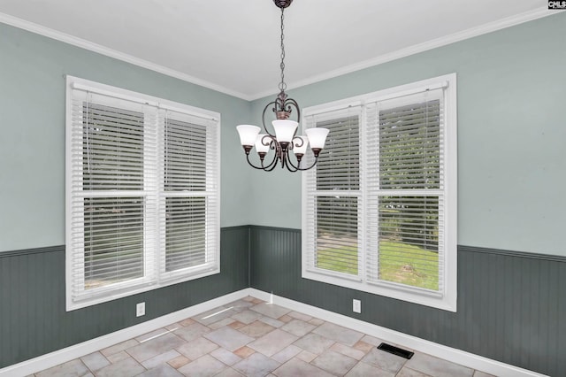 unfurnished dining area featuring ornamental molding and an inviting chandelier