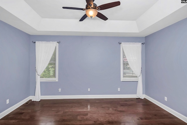 unfurnished room featuring a raised ceiling, wood-type flooring, and ceiling fan