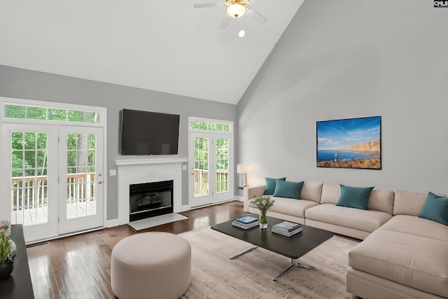 living room featuring hardwood / wood-style floors, high vaulted ceiling, a fireplace, and ceiling fan