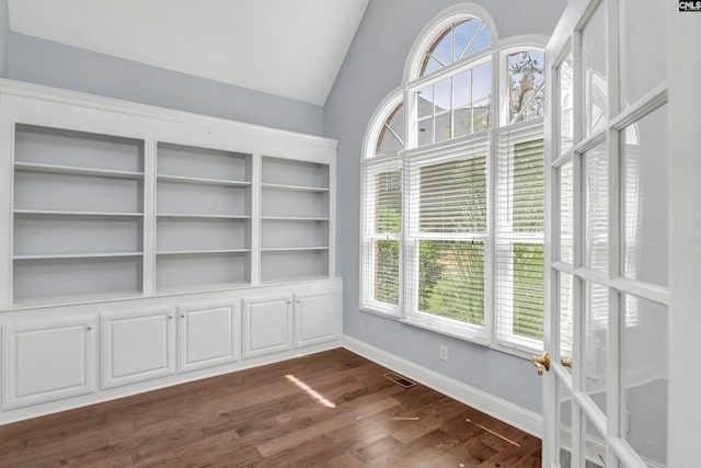 interior space with vaulted ceiling, built in features, a wealth of natural light, and dark hardwood / wood-style floors