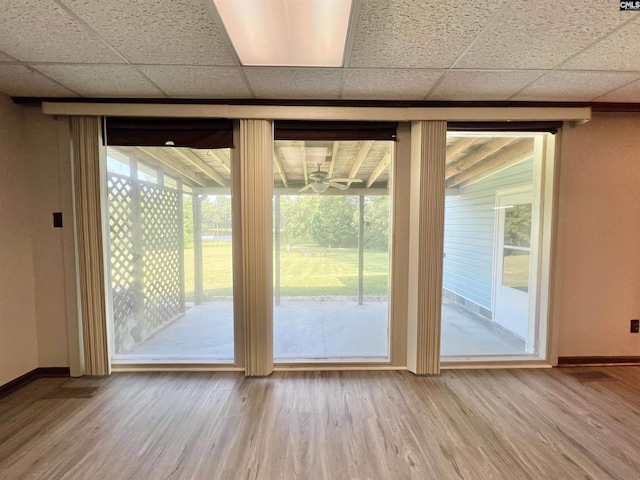 doorway to outside featuring a drop ceiling, baseboards, and wood finished floors