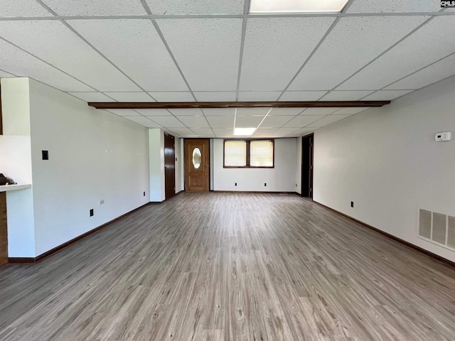 unfurnished living room featuring light wood finished floors, baseboards, visible vents, and a drop ceiling