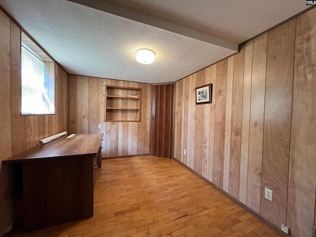 unfurnished office featuring wooden walls, baseboards, built in features, brick floor, and a textured ceiling