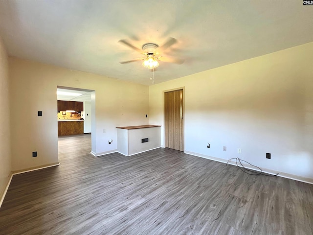 interior space featuring ceiling fan, baseboards, and dark wood finished floors