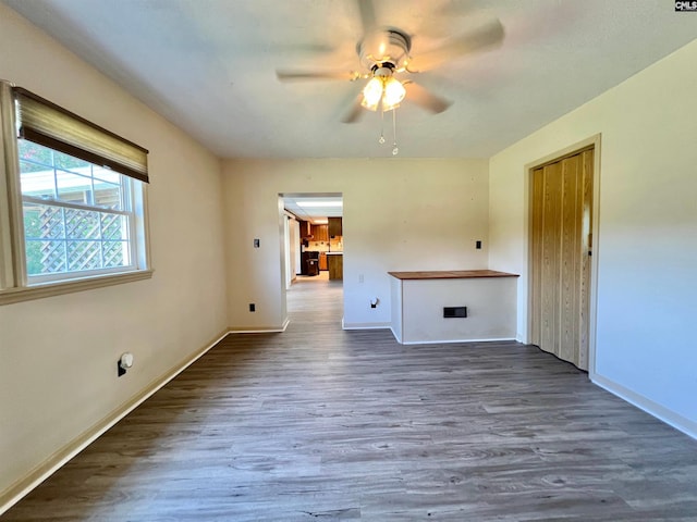 unfurnished room with ceiling fan, wood finished floors, and baseboards