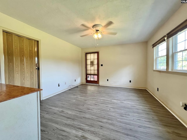 spare room featuring a textured ceiling, wood finished floors, a ceiling fan, and baseboards