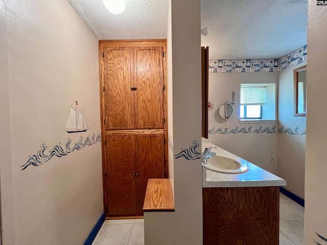 bathroom featuring a textured ceiling, tile patterned flooring, and baseboards