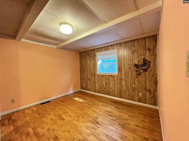 empty room with wood walls, baseboards, and visible vents