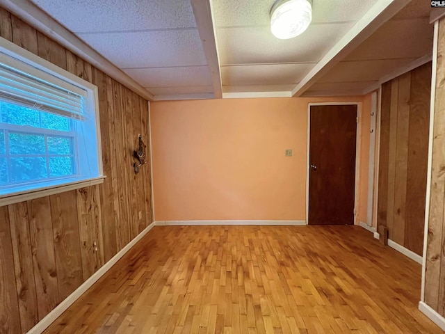 unfurnished room featuring wooden walls, baseboards, and wood finished floors