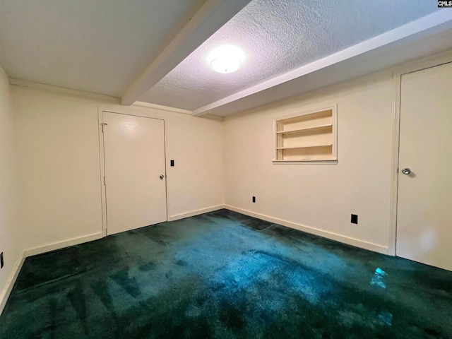 basement with baseboards, built in features, dark colored carpet, and a textured ceiling