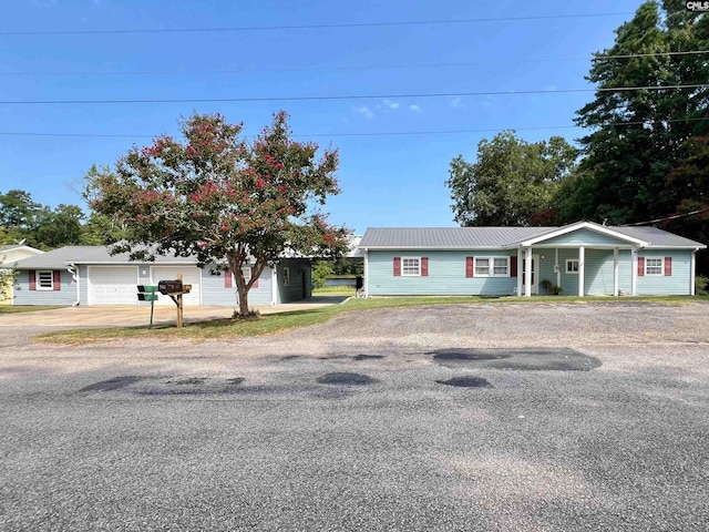 single story home with driveway and metal roof