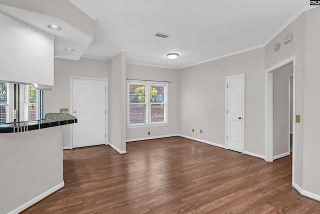 interior space featuring ornamental molding, a wealth of natural light, tile counters, and dark hardwood / wood-style floors