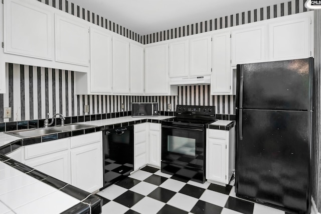 kitchen featuring black appliances, white cabinetry, custom range hood, and tile counters