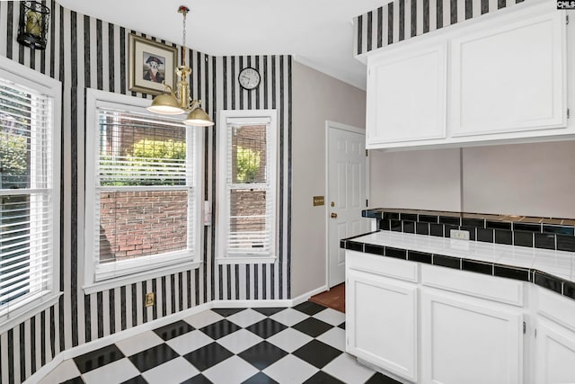 kitchen featuring a healthy amount of sunlight, pendant lighting, tile countertops, and white cabinets