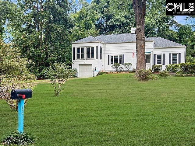 rear view of house featuring a yard and a garage