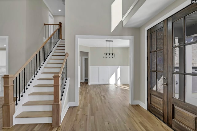 foyer entrance with a healthy amount of sunlight, light hardwood / wood-style flooring, and a notable chandelier