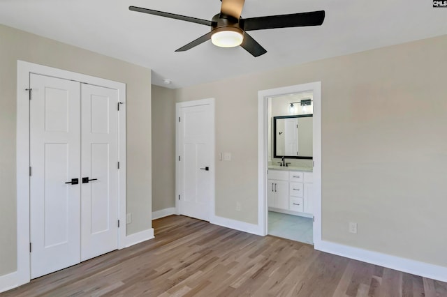 unfurnished bedroom featuring ensuite bath, light hardwood / wood-style flooring, a closet, and ceiling fan