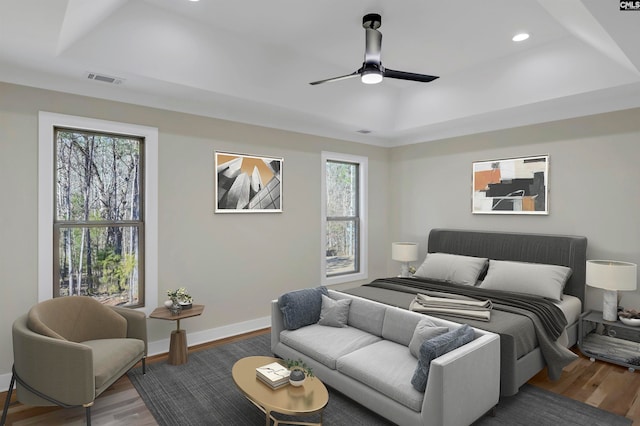 bedroom with ceiling fan, hardwood / wood-style flooring, and a raised ceiling