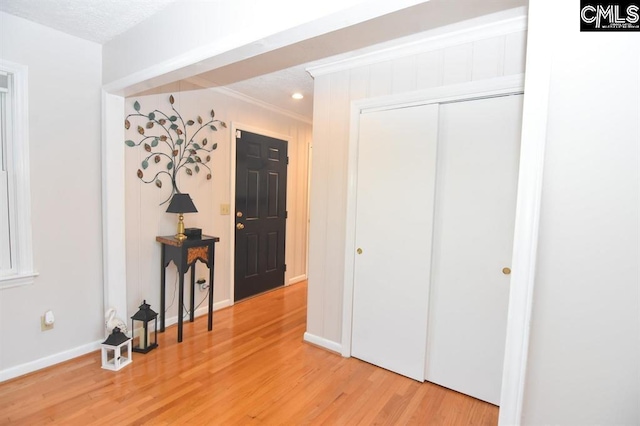 interior space with a textured ceiling, light hardwood / wood-style flooring, and ornamental molding