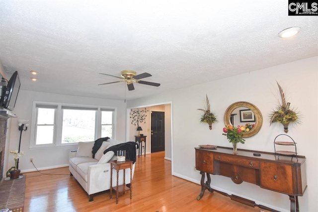 living room with a textured ceiling, hardwood / wood-style flooring, and ceiling fan