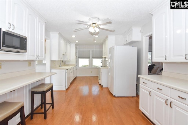 kitchen featuring white cabinetry, ceiling fan, a breakfast bar, white refrigerator, and light hardwood / wood-style floors