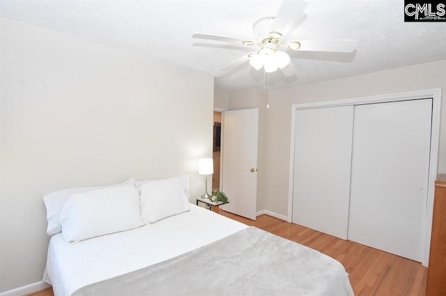 bedroom with light wood-type flooring, a closet, ceiling fan, and a textured ceiling