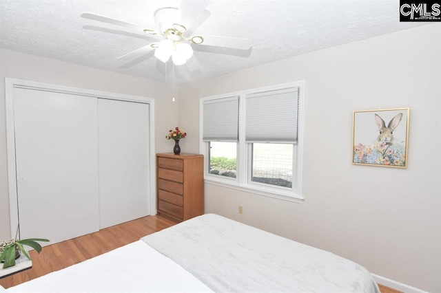 bedroom featuring a textured ceiling, ceiling fan, a closet, and light hardwood / wood-style floors