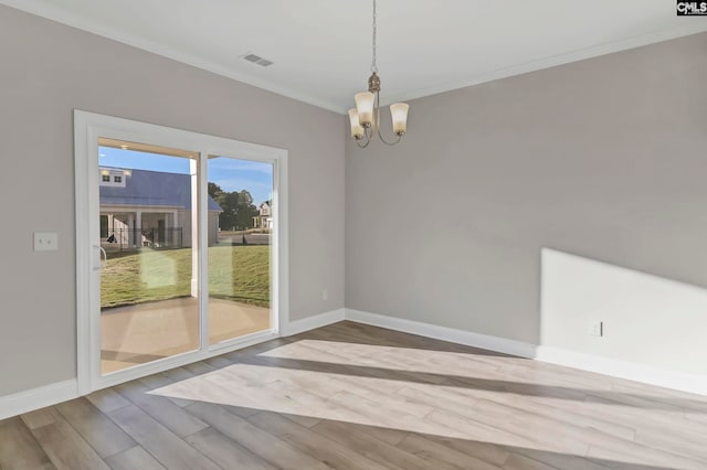 spare room with hardwood / wood-style flooring, an inviting chandelier, and crown molding