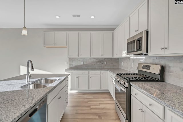 kitchen with light wood-type flooring, stainless steel appliances, decorative backsplash, and white cabinetry