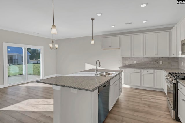 kitchen with appliances with stainless steel finishes, white cabinetry, an island with sink, and sink