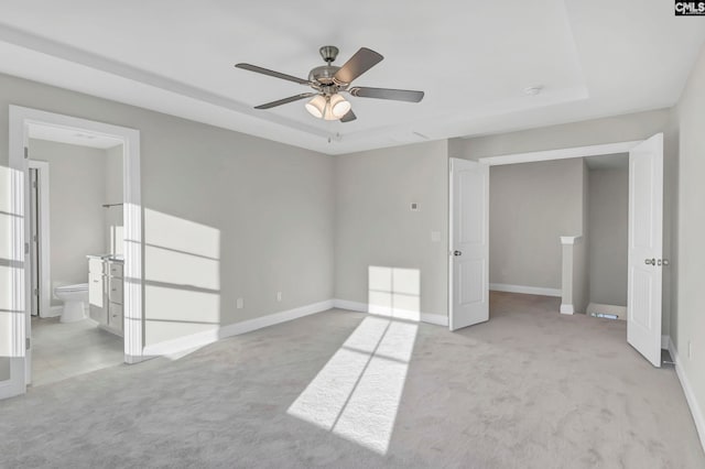 carpeted empty room with ceiling fan and a raised ceiling