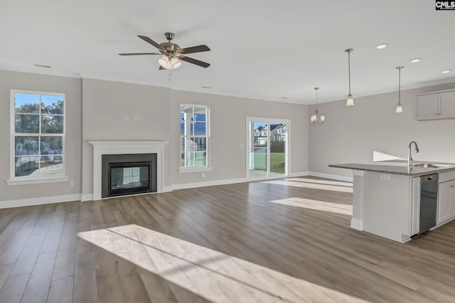 unfurnished living room with light wood-type flooring, ceiling fan with notable chandelier, and sink