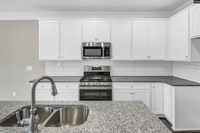 kitchen featuring appliances with stainless steel finishes, white cabinetry, sink, and decorative backsplash