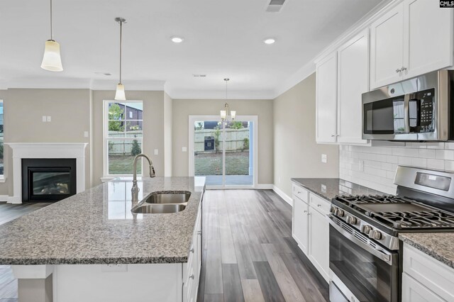 kitchen with appliances with stainless steel finishes, an island with sink, sink, hardwood / wood-style flooring, and white cabinetry