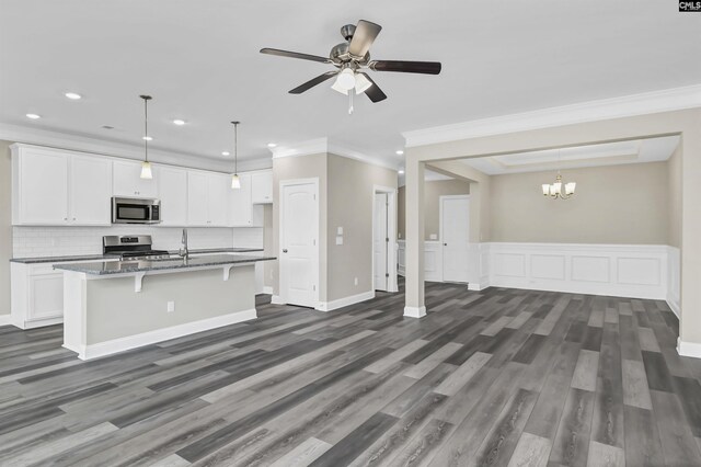 kitchen with ceiling fan with notable chandelier, appliances with stainless steel finishes, dark stone counters, and white cabinetry