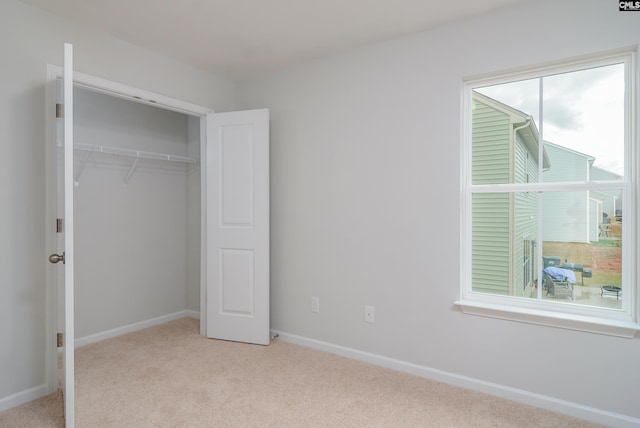 unfurnished bedroom with light carpet and a closet