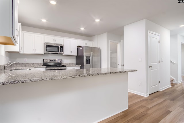 kitchen featuring light wood-type flooring, sink, light stone countertops, appliances with stainless steel finishes, and white cabinets