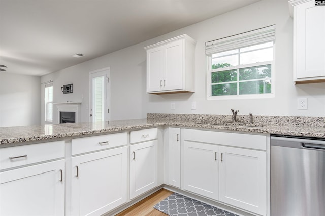 kitchen featuring light stone countertops, light hardwood / wood-style flooring, stainless steel dishwasher, sink, and white cabinets