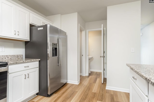 kitchen featuring light wood-type flooring, light stone countertops, stainless steel appliances, and white cabinets