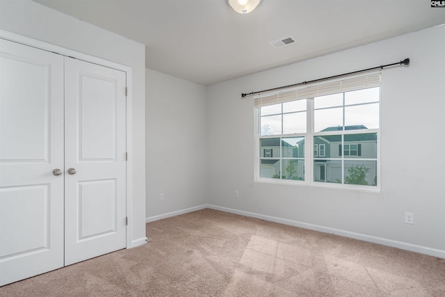 unfurnished bedroom featuring a closet and light colored carpet