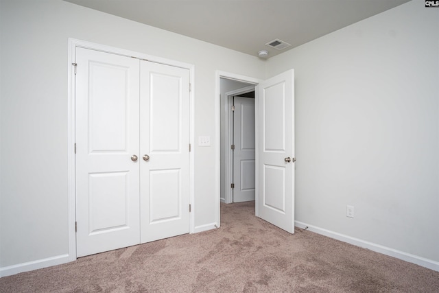 unfurnished bedroom with a closet and light carpet