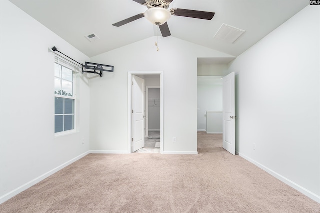 unfurnished bedroom featuring lofted ceiling, light colored carpet, and a spacious closet