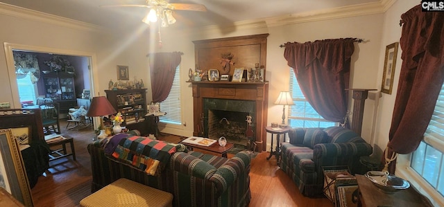 living room with wood-type flooring, ceiling fan, crown molding, and a premium fireplace