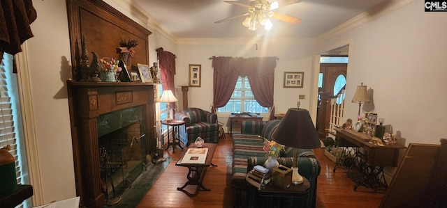 living room featuring a tile fireplace, crown molding, ceiling fan, and dark wood-type flooring