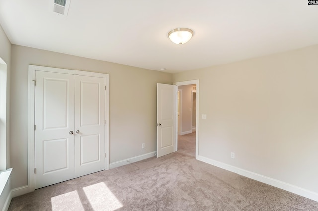 unfurnished bedroom featuring light colored carpet and a closet