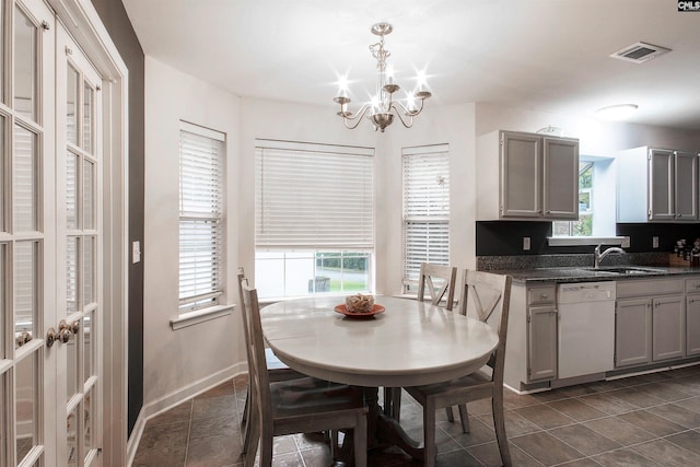 dining room with sink, dark tile patterned flooring, and a notable chandelier